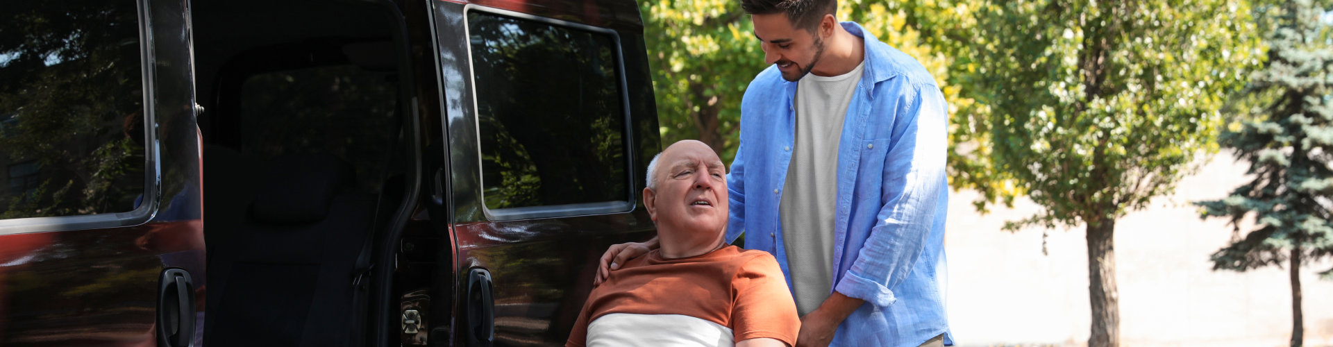 image of the senior man in a wheelchair assisted with the adult guy